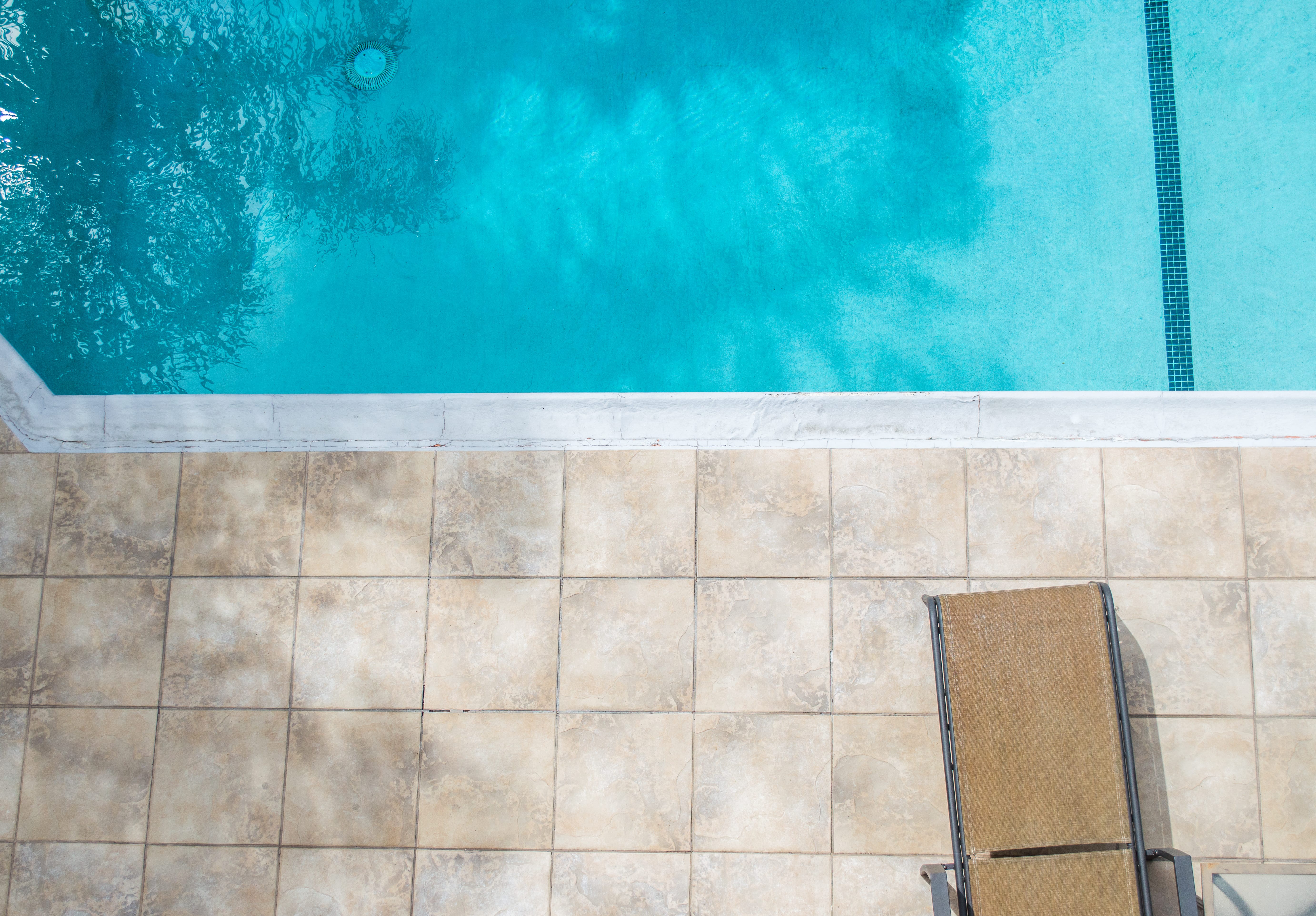 empty,pool,deck,with,lounge,chair,next,to,neglected,swimming